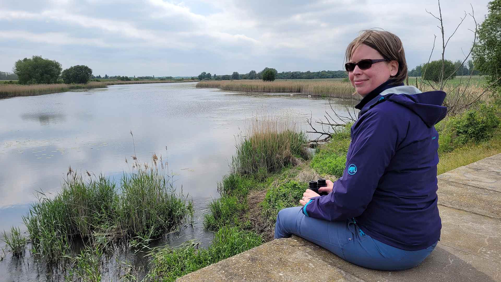 Die Vogelguckerin Silke Hartmann sitzt an einem See.